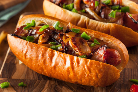Sausage in a long bread roll topped with onion and spring onions.