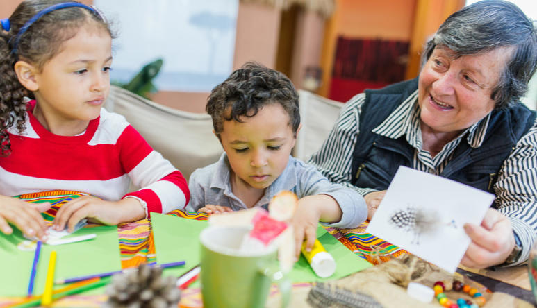Families making craft In Ranger Kids, showing two young guests, left, with an elder volunteer, right.
