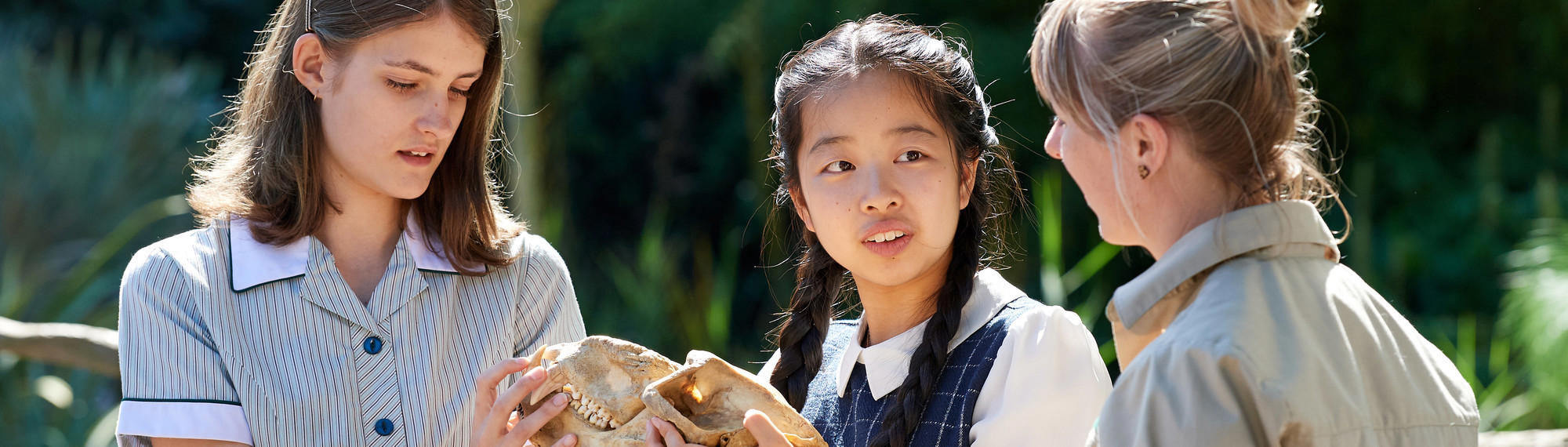 Two school students look at an animal skull as a Zoo staff member talks to them.