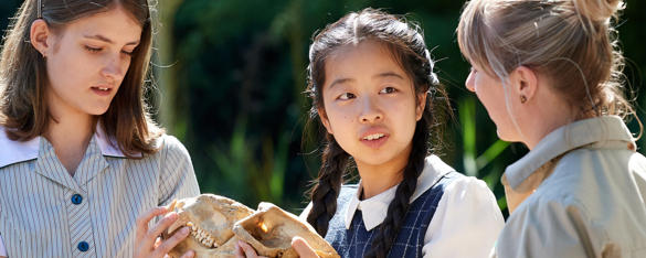 Two school students look at an animal skull as a Zoo staff member talks to them.