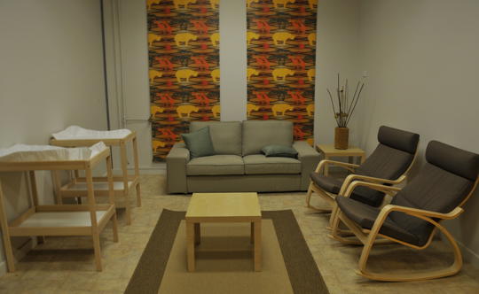 A room with a couch, two lounge chairs and two change tables.