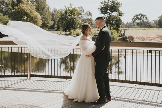 Wedding Couple Standing On Boardwalk with a river behind them