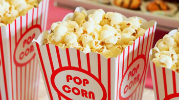 Close-up of three popcorn tubs in a row, decorated in red stripes on white.